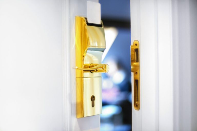 Close-up of a golden door lock on a white door, partially open.